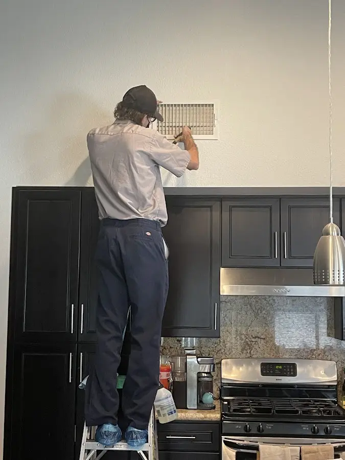 Technician inspecting an air vent during HVAC service in Fairhope